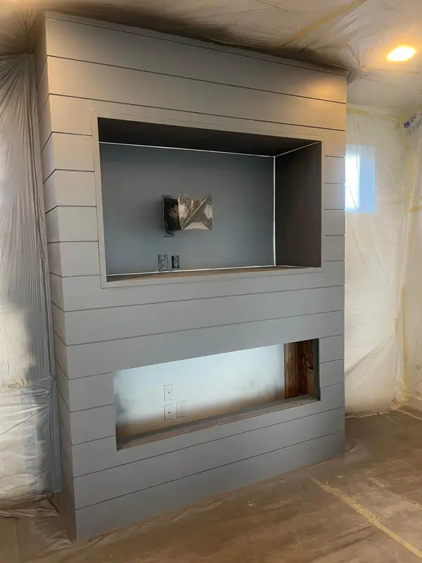 Shiplap TV wall in progress, with paper on the floor and plastic on the walls